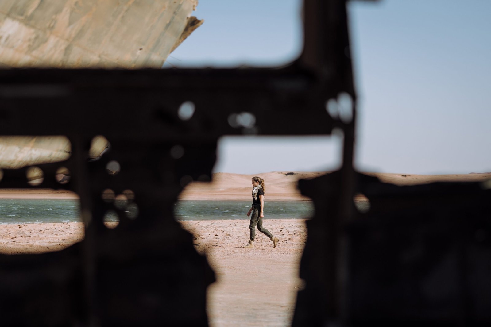 a person walking on a beach with a boat in the background